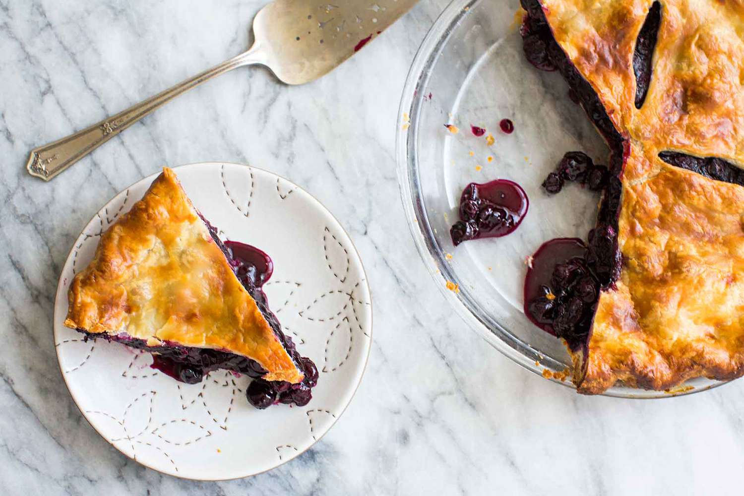 Overhead of a Blueberry Pie with a slice cut out and resting on a plate