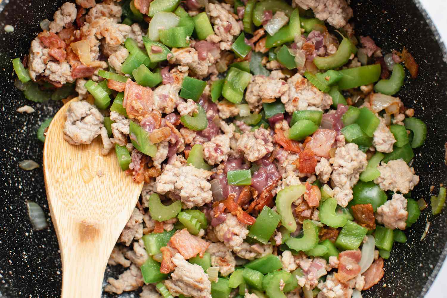 Mixing in meat for a dirty rice recipe.