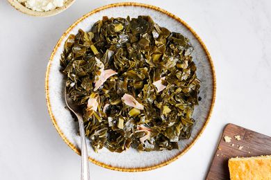 Instant Pot Collard Greens on a Plate with Serving Utensil Next to a Bowl of Mashed Potatoes and Cornbread