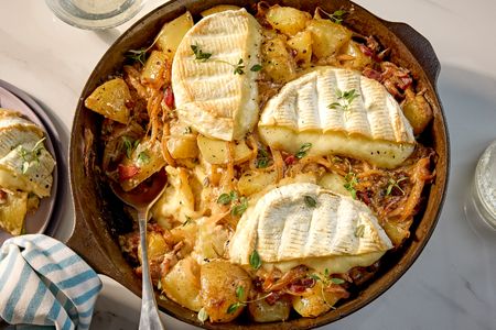Skillet of tartiflette with melted cheese and potatoes served on a table