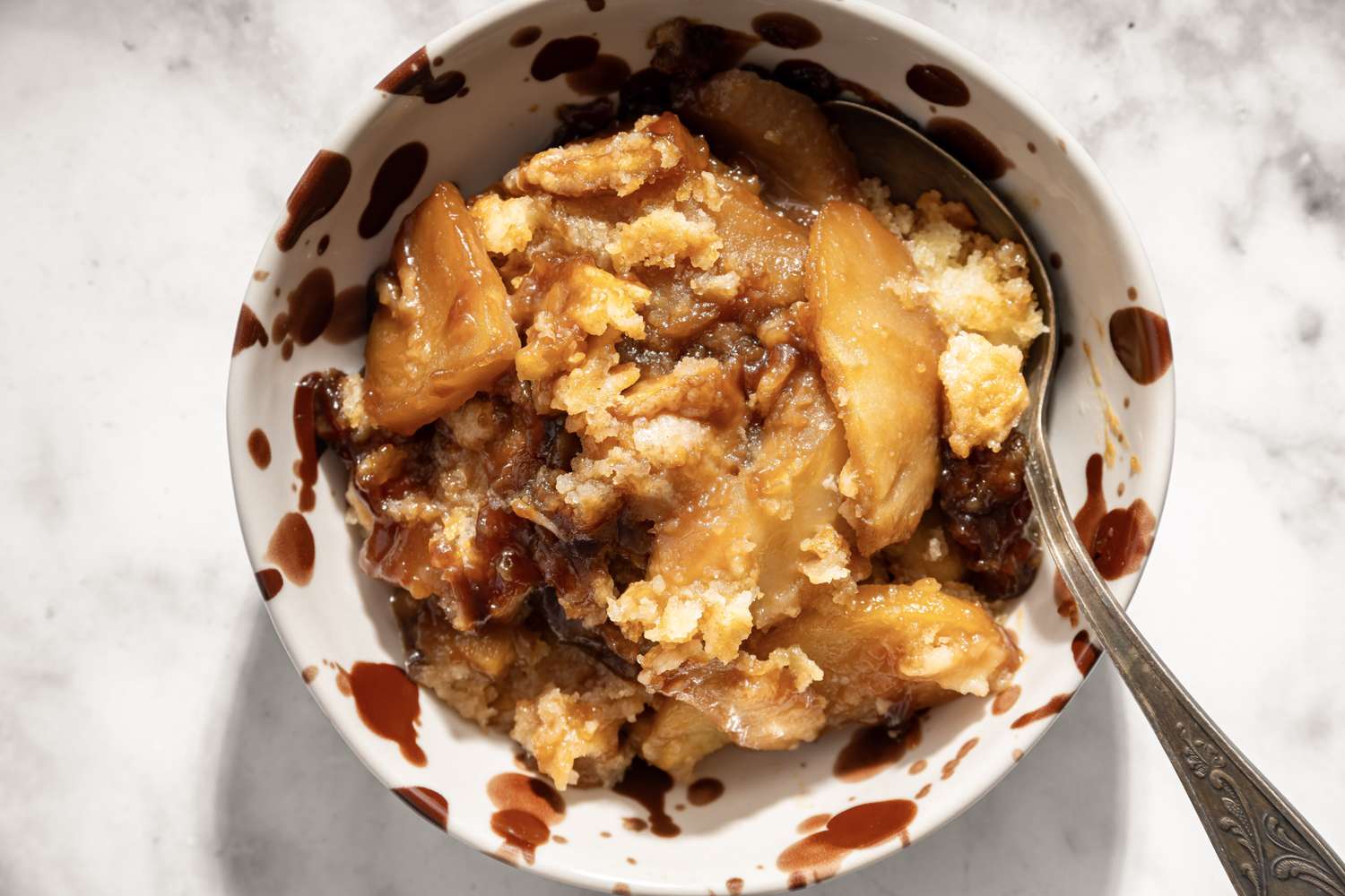 Caramel apple cobbler served in a bowl with a spoon