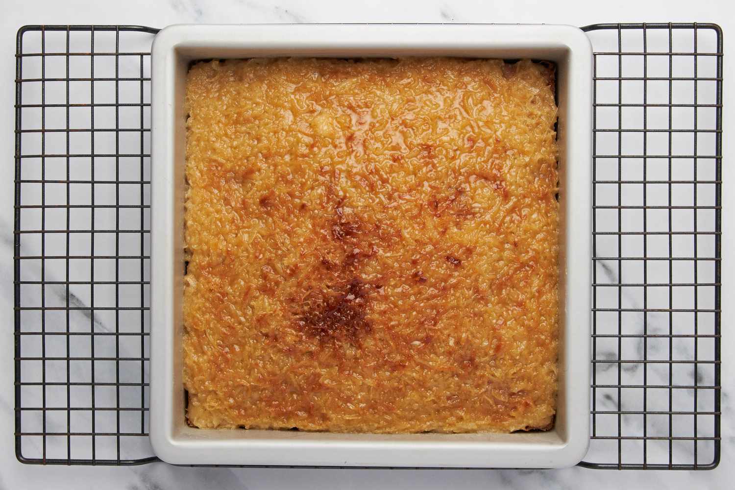 Lazy daisy cake (with coconut topping) cooling on a wire rack after broiled