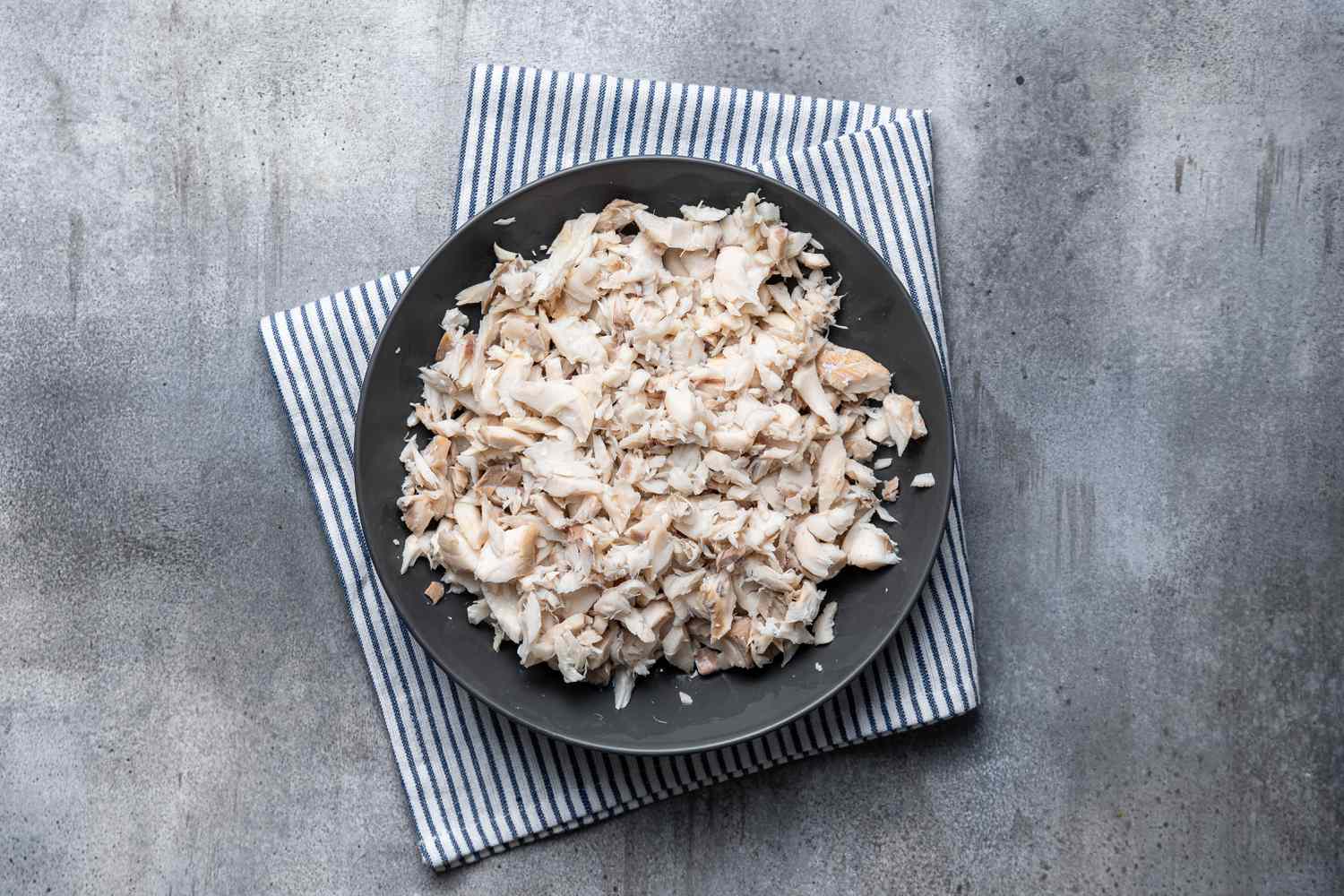 Flakes of cooked cod on a plate to make a Cod Fish Cakes recipe