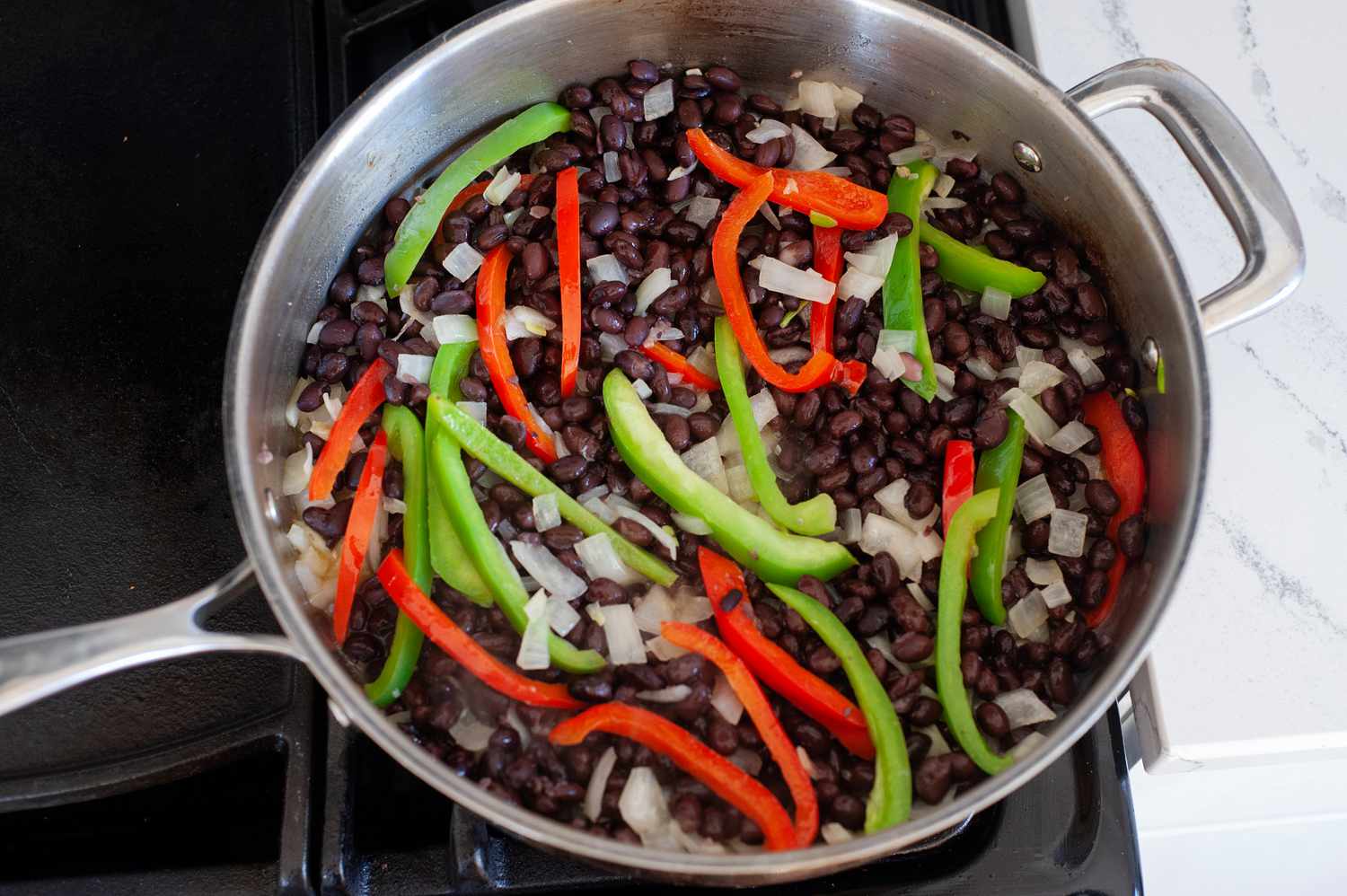 Black beans added to the rice and bell peppers to make a black beans and rice recipe.
