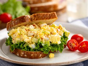 Egg salad sandwich with lettuce on whole grain bread and grape tomatoes on a plate