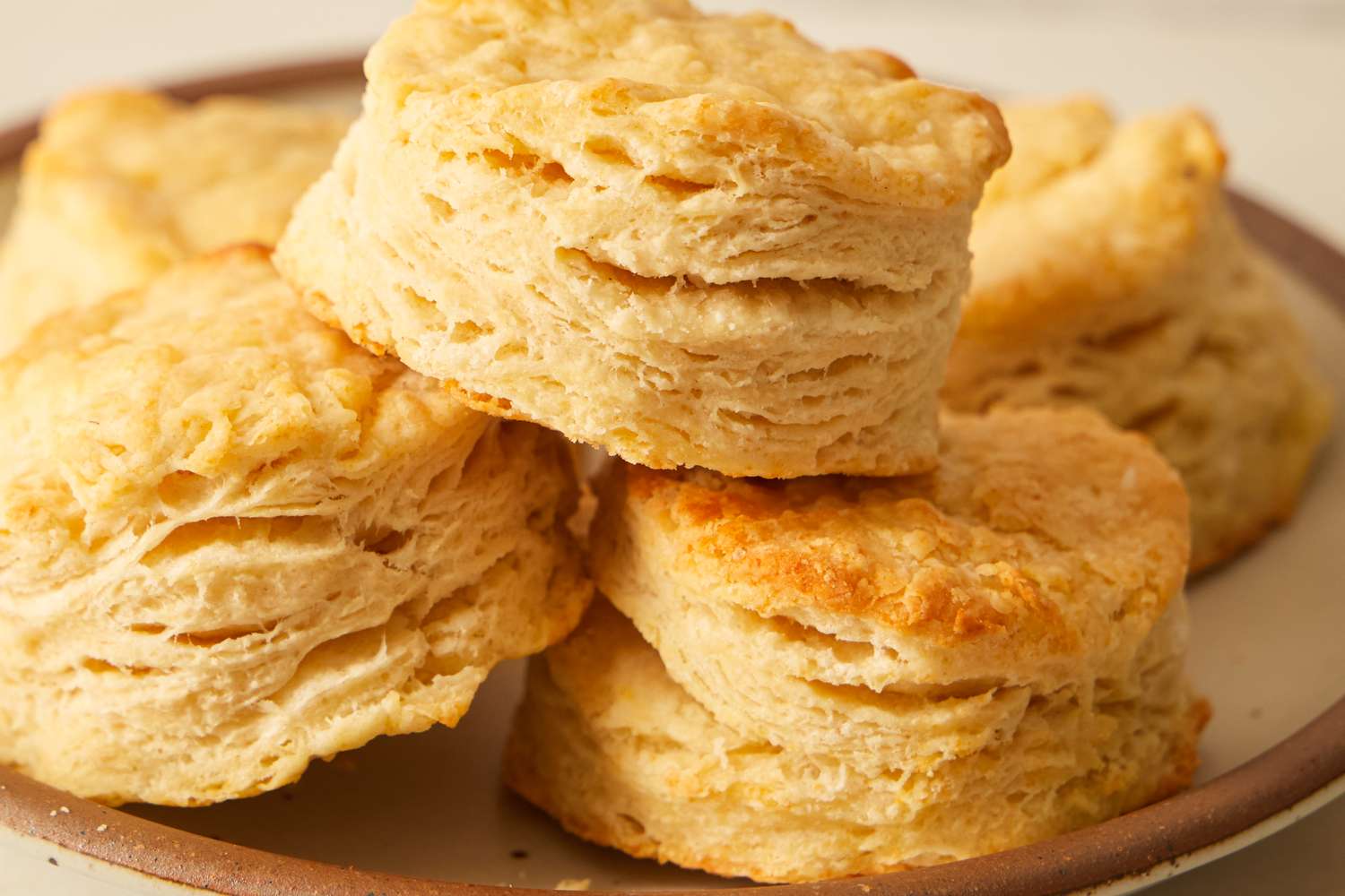 A plate stacked with buttery flaky baked biscuits