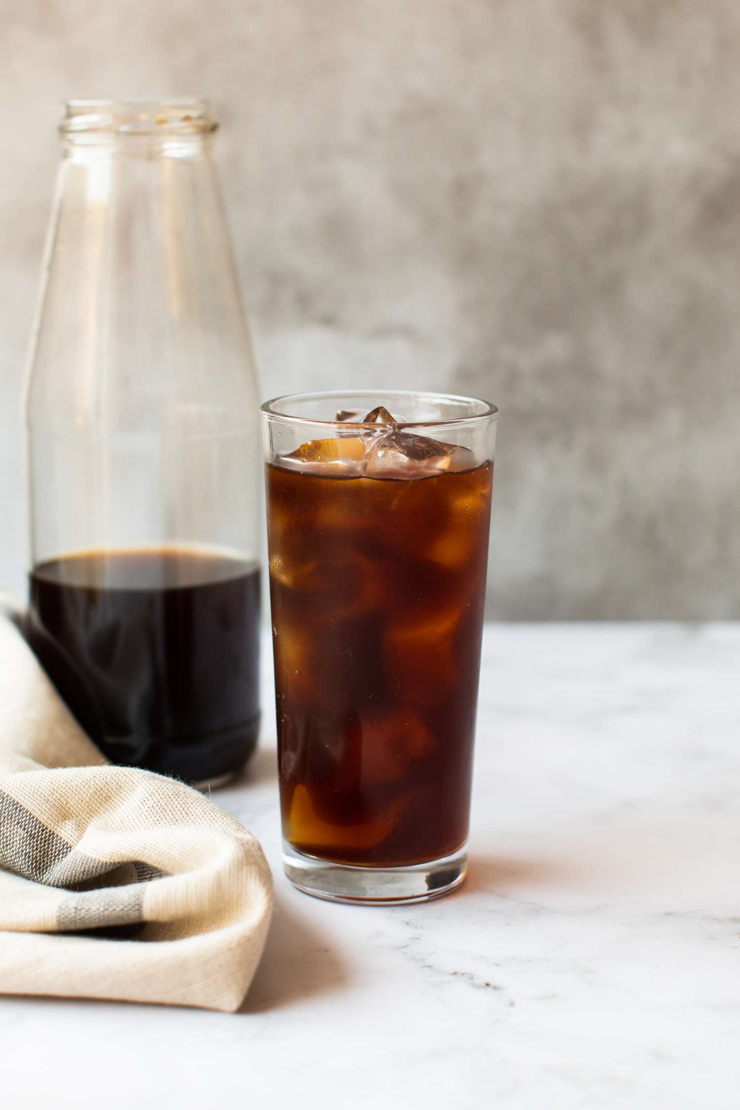 A glass of Ice Cold Brew Coffee with a pitcher in the background 