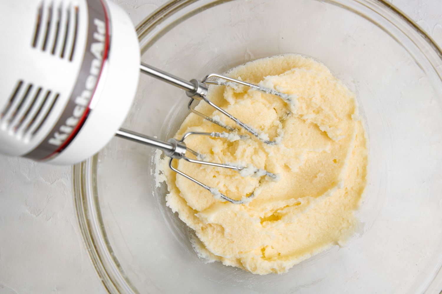 Creaming butter and sugar with a hand mixer to make apple bread with streusel.