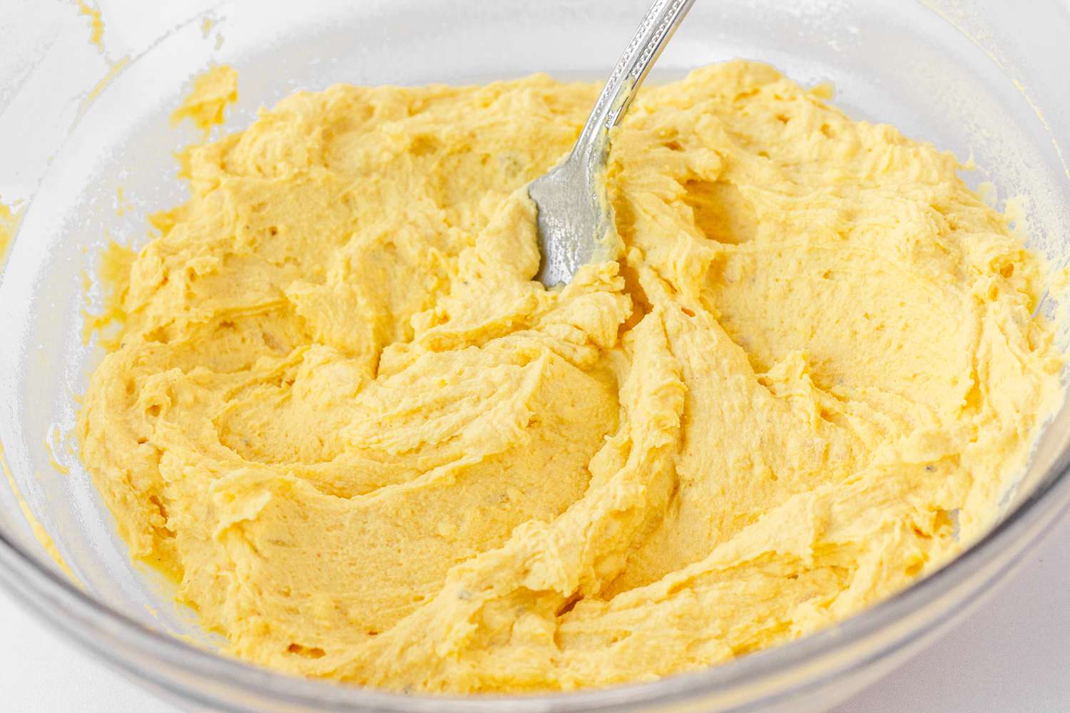 Mixing the filling in a glass bowl to make Classic Deviled Eggs.