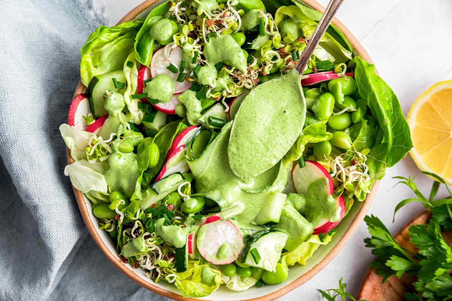 Green salad with radishes sprouts and green goddess dressing in a bowl