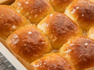 Freshly baked dinner rolls in a baking dish topped with coarse salt