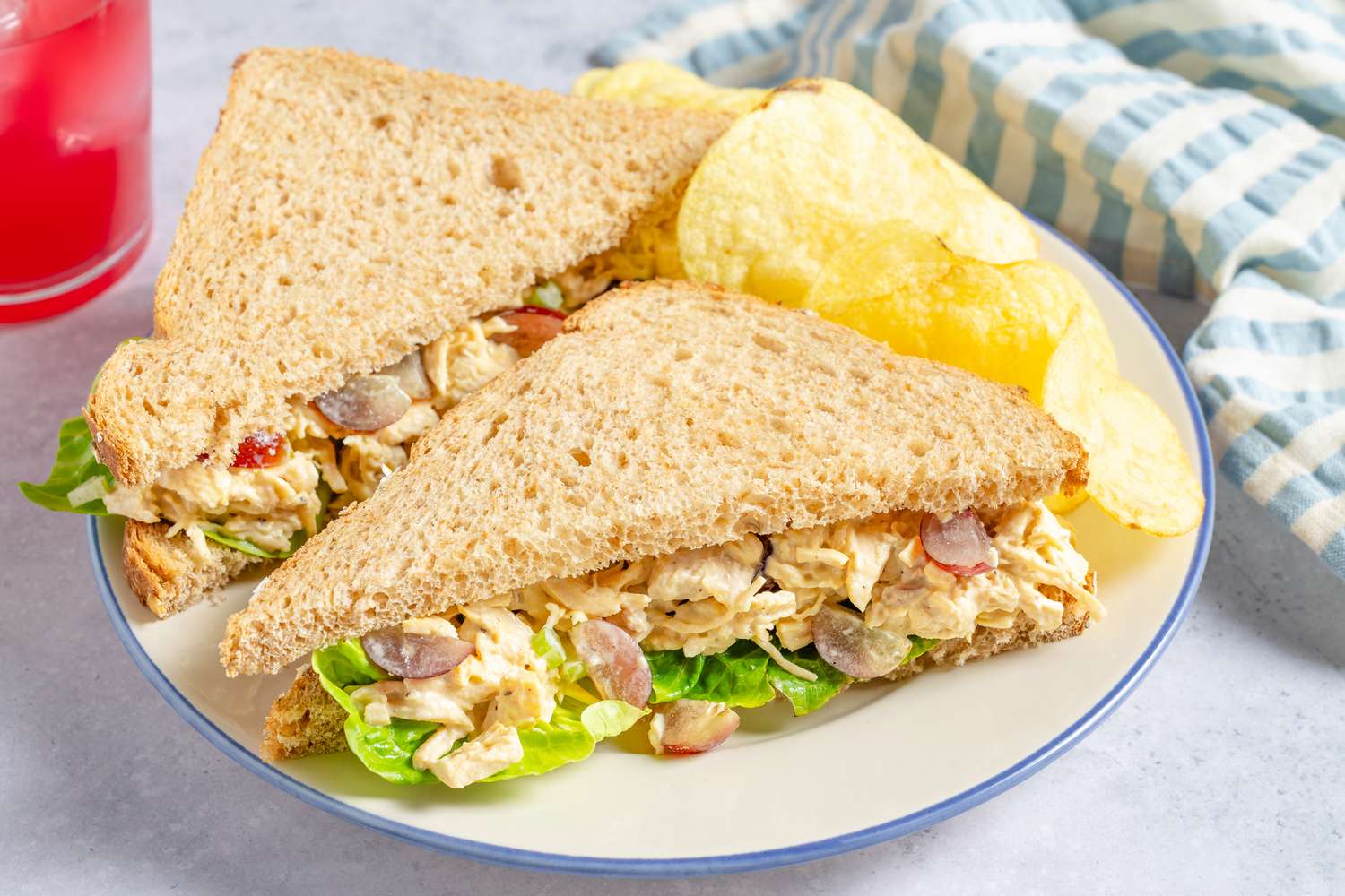 Chicken Salad with Grapes sandwich cut in half with a side of potato chips