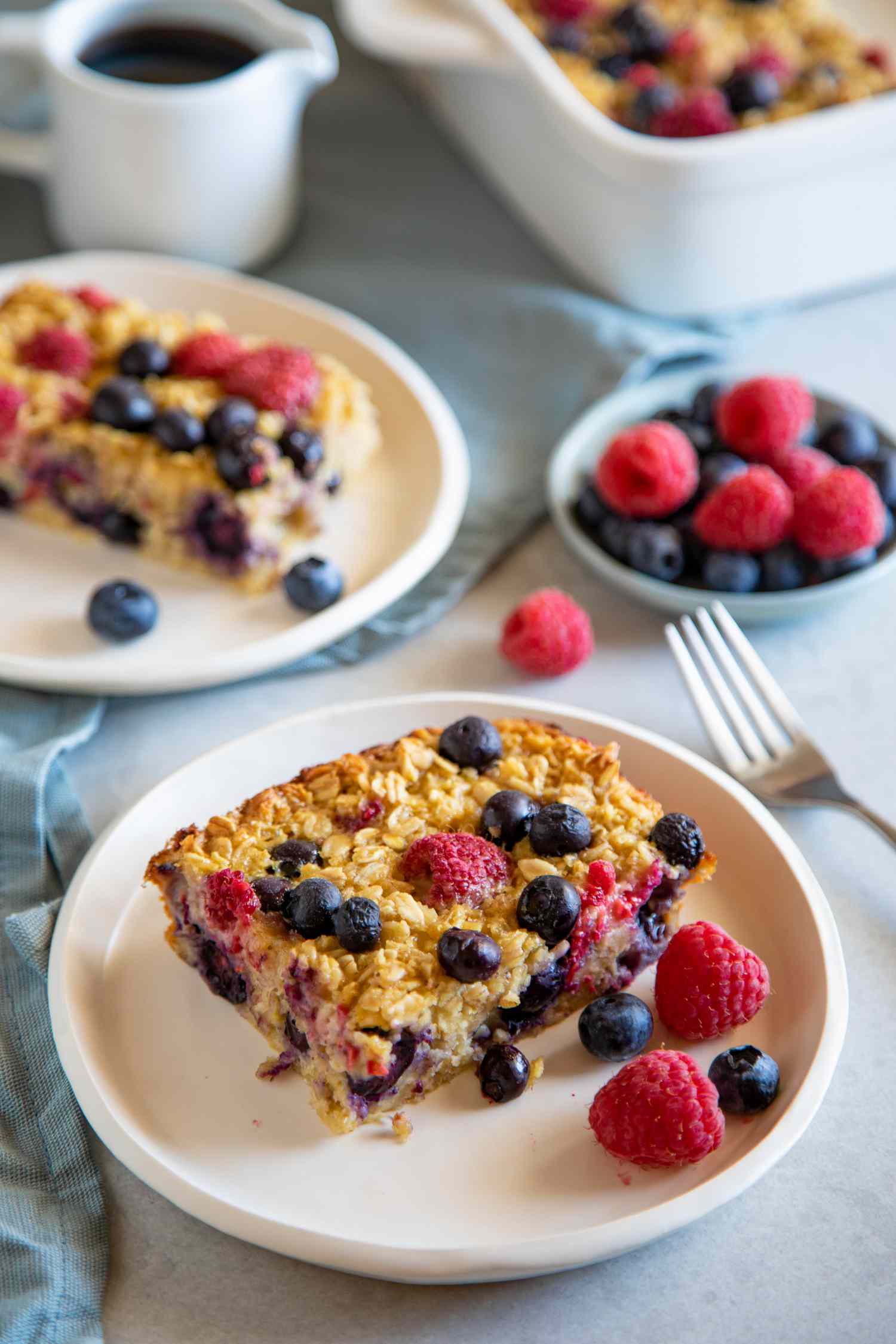 Baked Oatmeal Bars served on a plate and topped with berries with maple syrup and extra berries set behind the plate.