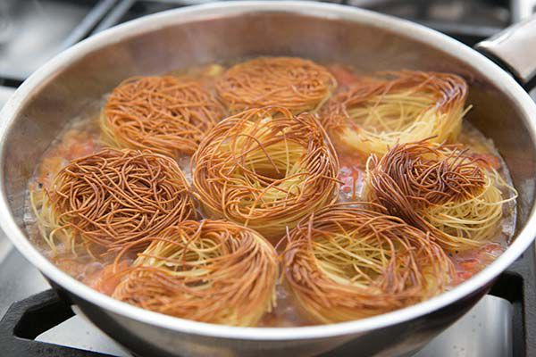 All the browned angel hair pasta nests together in a pan