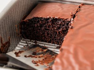 Chocolate Depression cake in a baking pan with a couple of slices taken out and a spatula