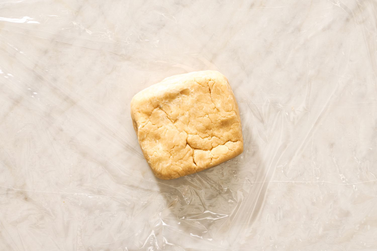 crust shaped into a square on a piece of plastic wrap for peach and raspberry pandowdy recipe