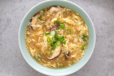 Bowl of egg drop soup with mushrooms and spring onions