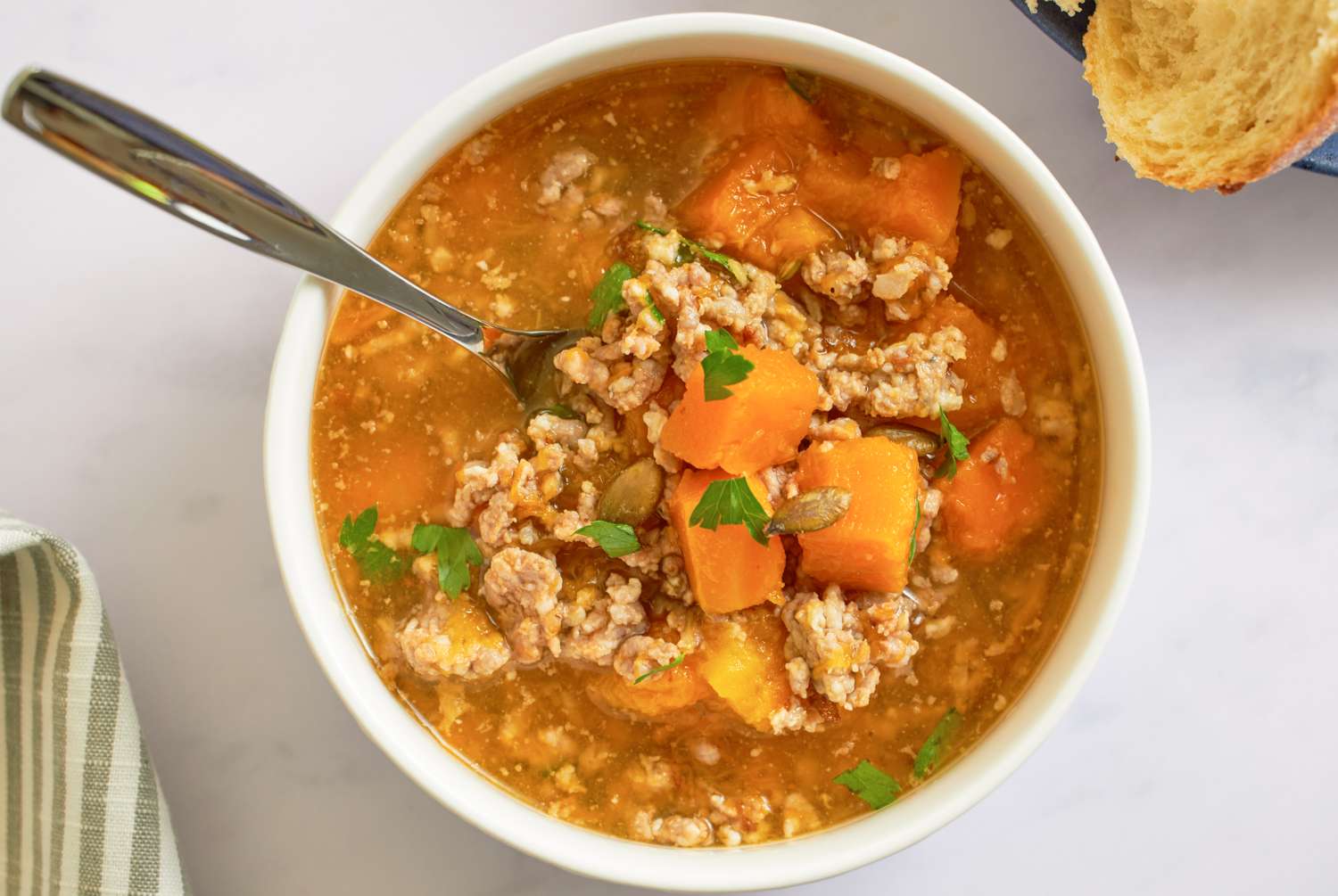 A bowl of butternut squash and sausage soup with a spoon