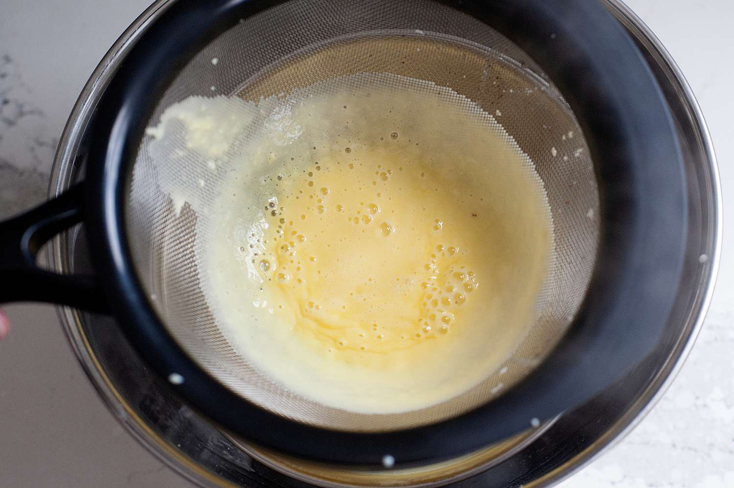 Straining base of mint chocolate chip ice cream over a water bath.