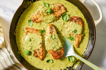 Chicken breasts cooked in pesto sauce and garnished with basil in a skillet
