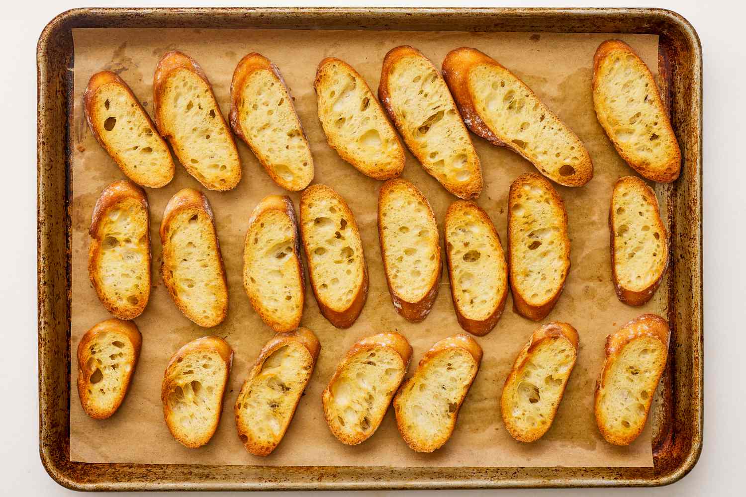 toasted baguette pieces on a parchment paper lined baking sheet for tomato pie dip recipe