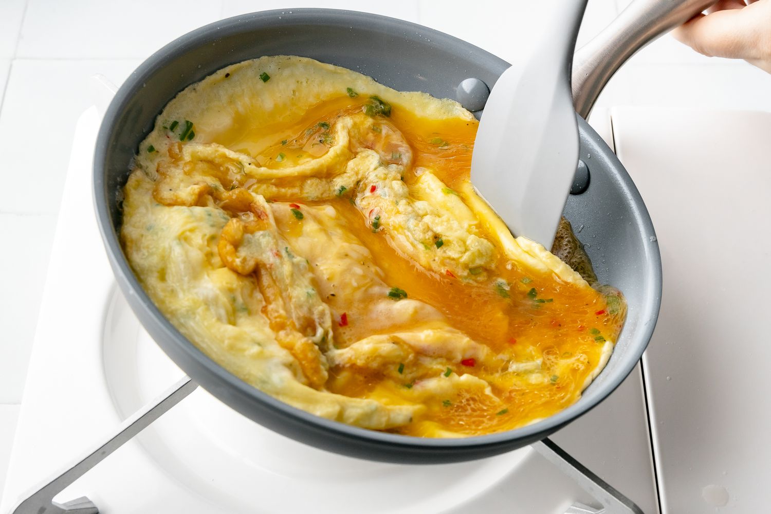 With Pan Tilted Slightly, Spatula Pushes Thai Omelet Edge to the Center, Allowing Remaining Raw Egg Mixture to Contact the Skillet