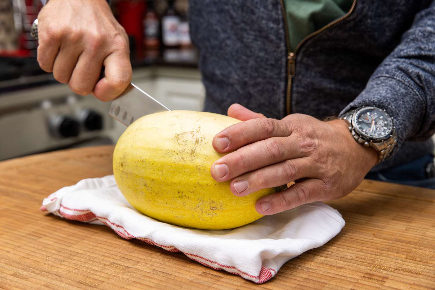 Spaghetti Squash Carefully Cut in Half While Placed on a Folded Kitchen Towel for Spaghetti Squash Soup with Italian Sausage Recipe
