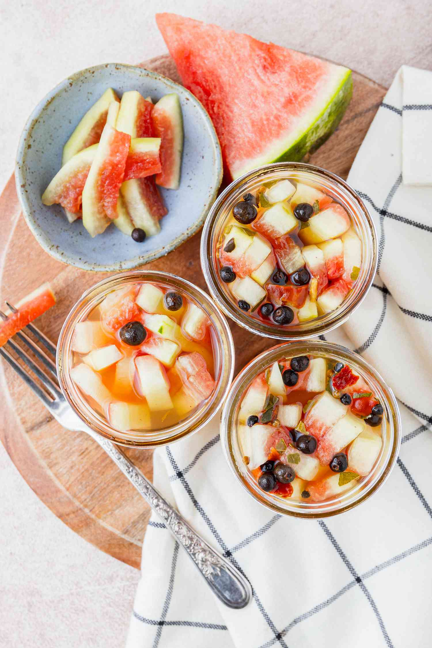 Pickled Watermelon Rinds in Jars Next to a Bowl with More Pickles