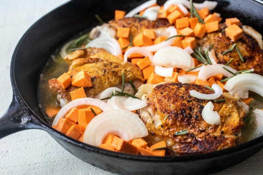Cider-Braised Chicken Thighs with Sweet Potatoes in cast iron skillet