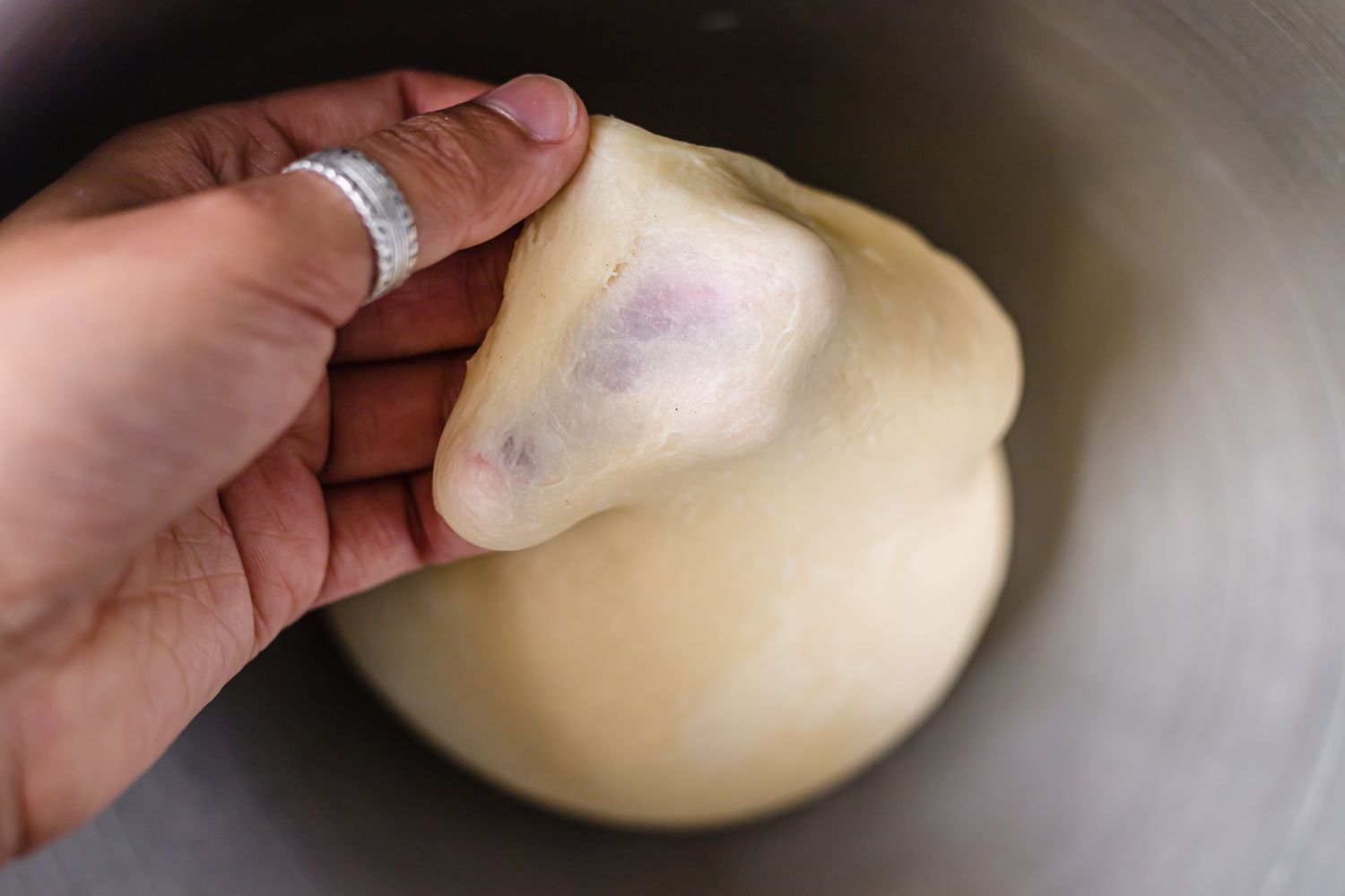Checking the strength of the dough for pull apart rolls with garlic and parmesan.