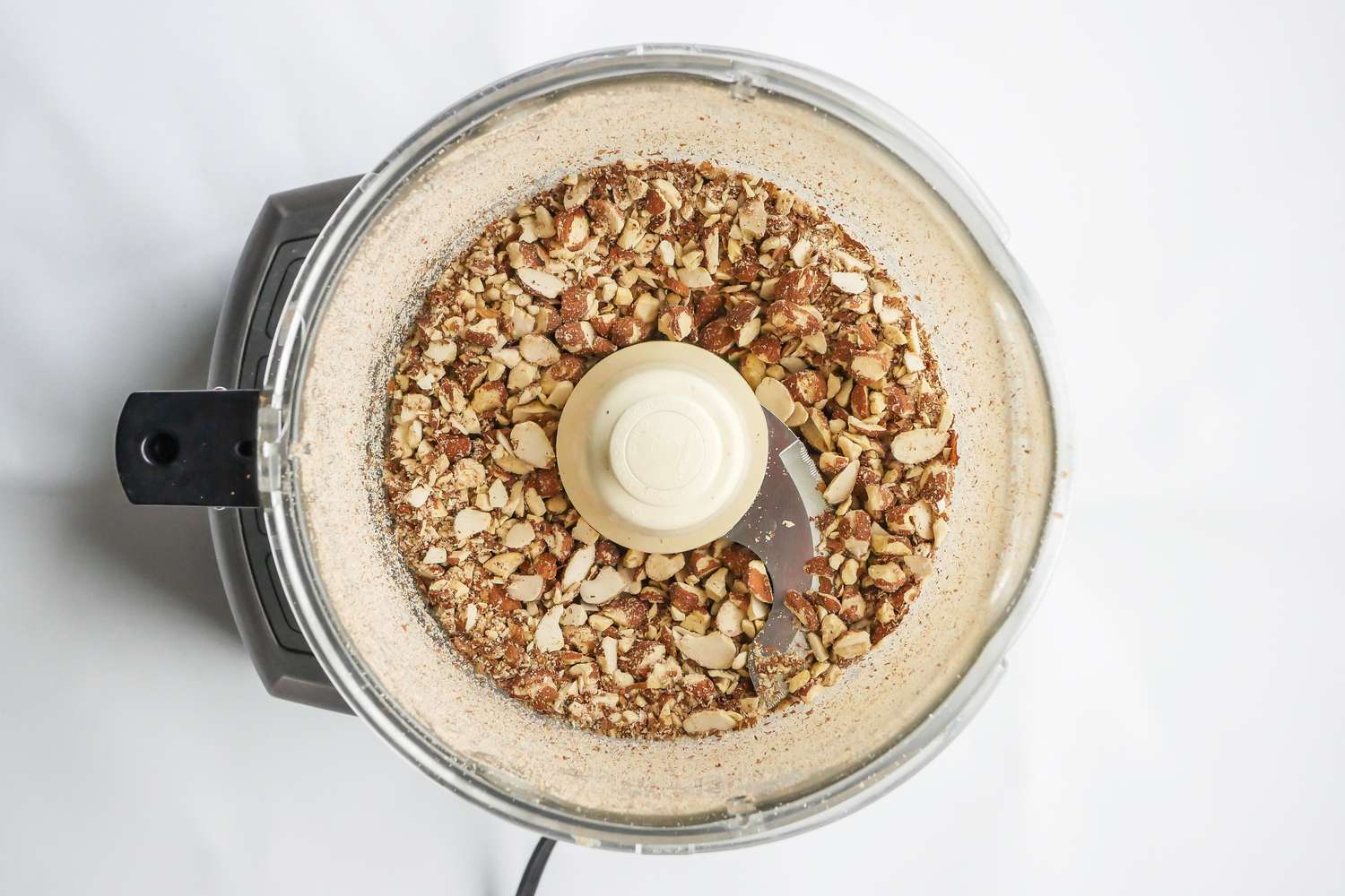 Overhead view of a food processor filled with almonds to make an Orgeat recipe.