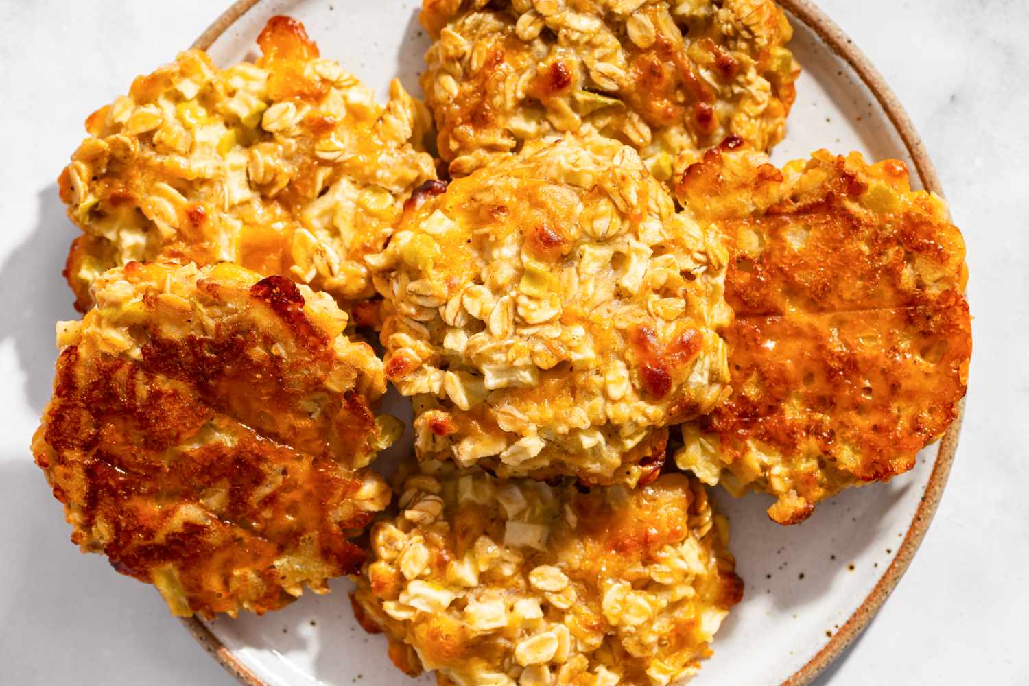 A plate of apple cheddar oat cookies with a few cookies flipped over to show the cheesy bottoms.