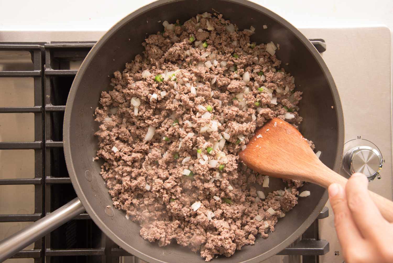Ground Chuck Cooked with Onions in a Skillet and Stirred with a Wooden Spoon for Beef Enchilada Casserole Recipe