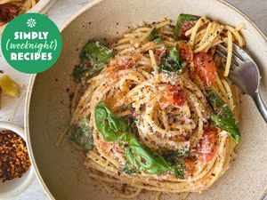 A bowl of pasta garnished with spinach and red pepper flakes, Simply Recipes logo in the corner