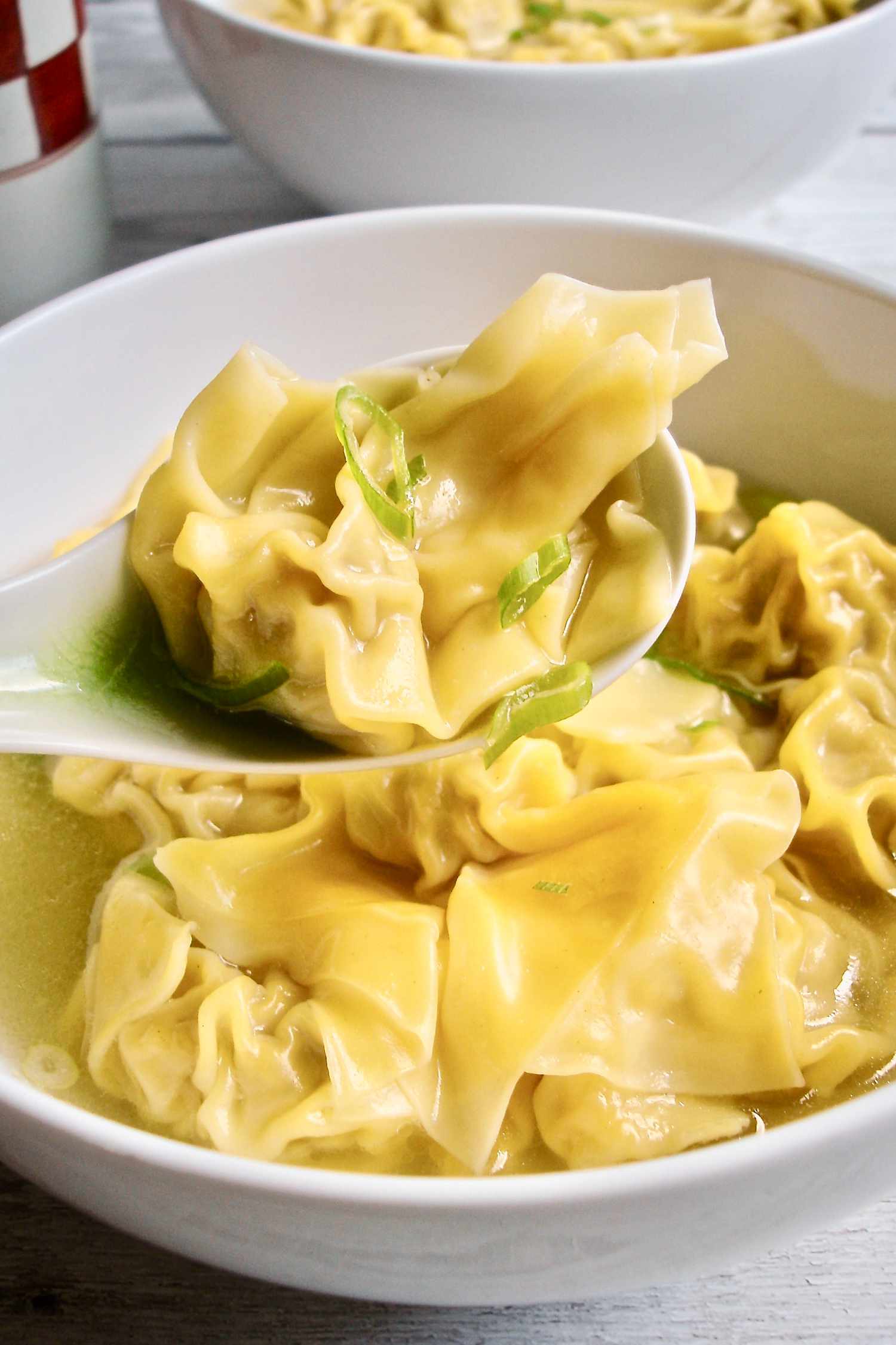 Homemade pork wonton soup scooped with a soup spoon.