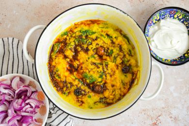 Daal Palak in a Dutch Oven on the Counter Next to a Bowl of Yogurt and a Bowl of Pickled Onions