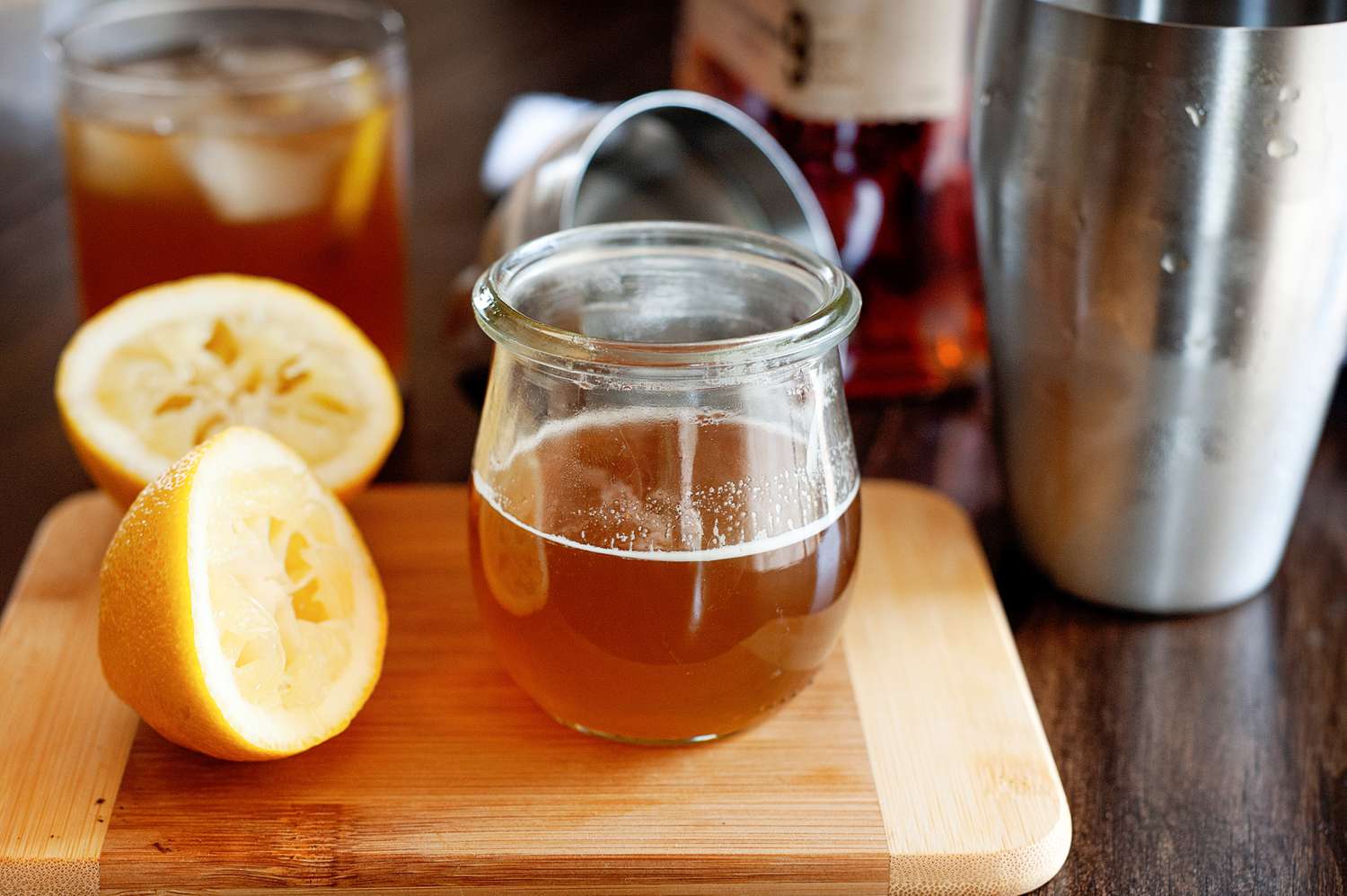 Essential bourbon cocktail: The Gold Rush cocktail on a cutting board next to halved lemon.