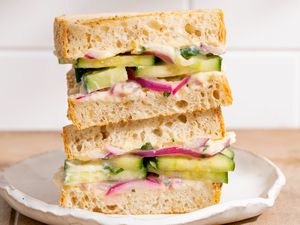 Stacked cucumber and red onion sandwiches on a white plate