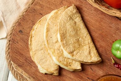 Three folded cheese quesadillas arranged on a wooden board