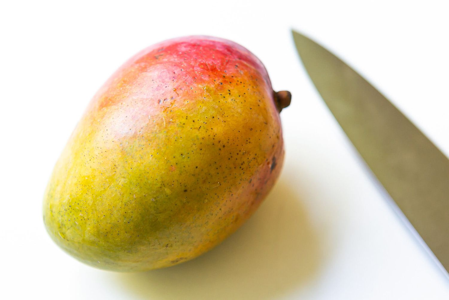 Ripe mango on a cutting board with a knife