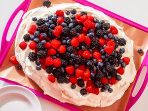 berry pavlova on a parchment paper lined tray