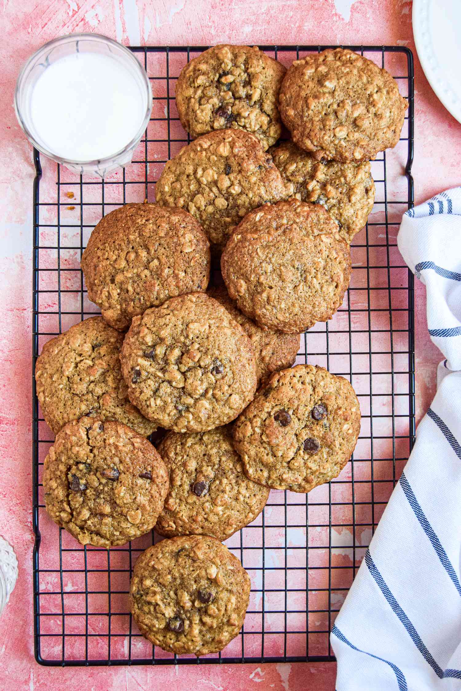 Oatmeal Banana Cookies on a Wire Rack Next to a Glass of Milk and a Kitchen Towel