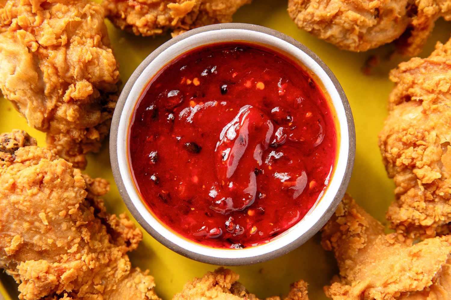 A bowl of sweet and sour sauce surrounded by pieces of fried chicken