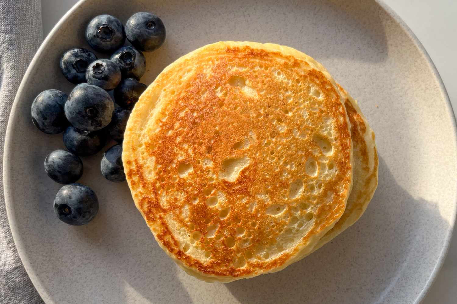 Pancakes on a plate with blueberries on the side
