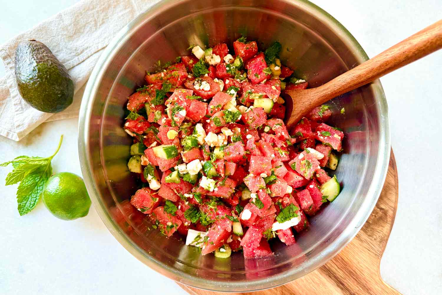 Bowl of chopped watermelon salad with a wooden spoon on a table