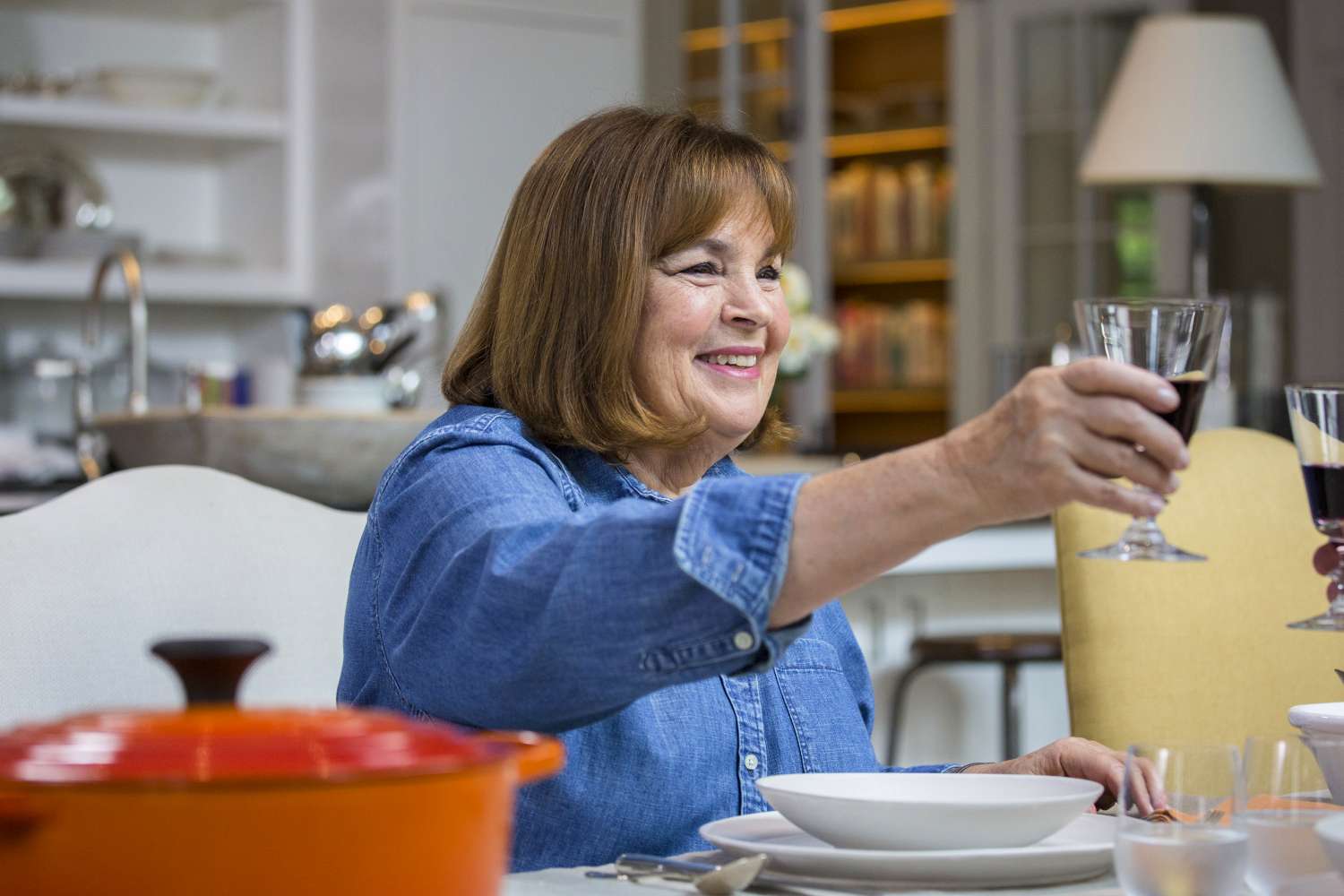 Ina Garten raising a wine glass at a dining table