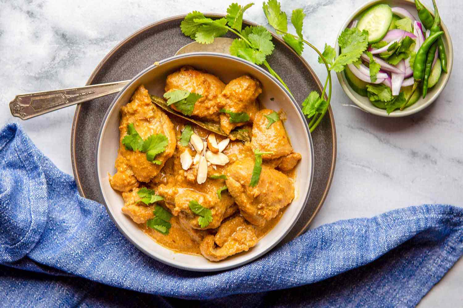 Easy Chicken Korma Recipe - bowl of chicken with sauce, herbs and almonds