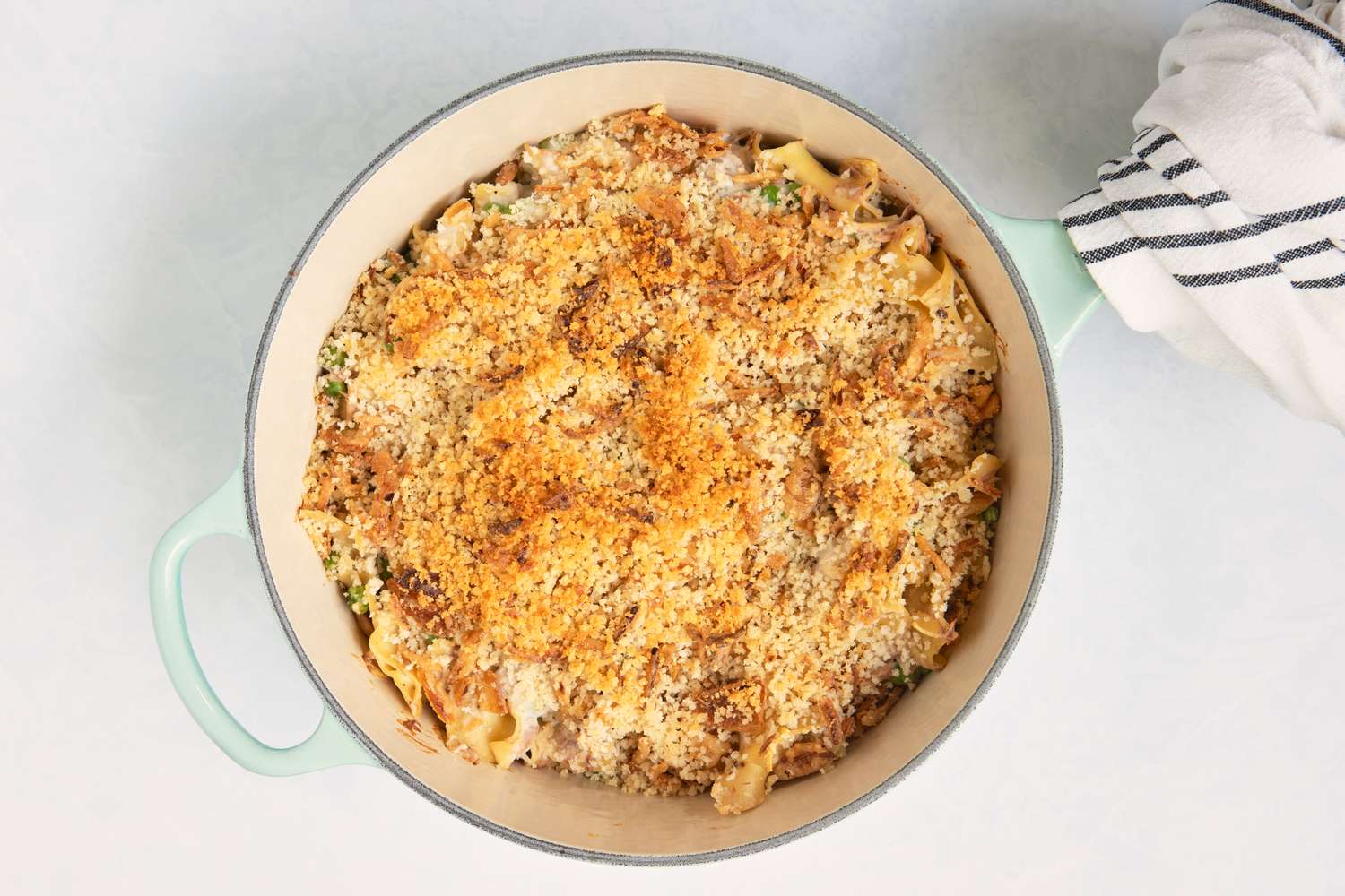 Casserole with a breadcrumb topping served in a round dish napkin visible on the side