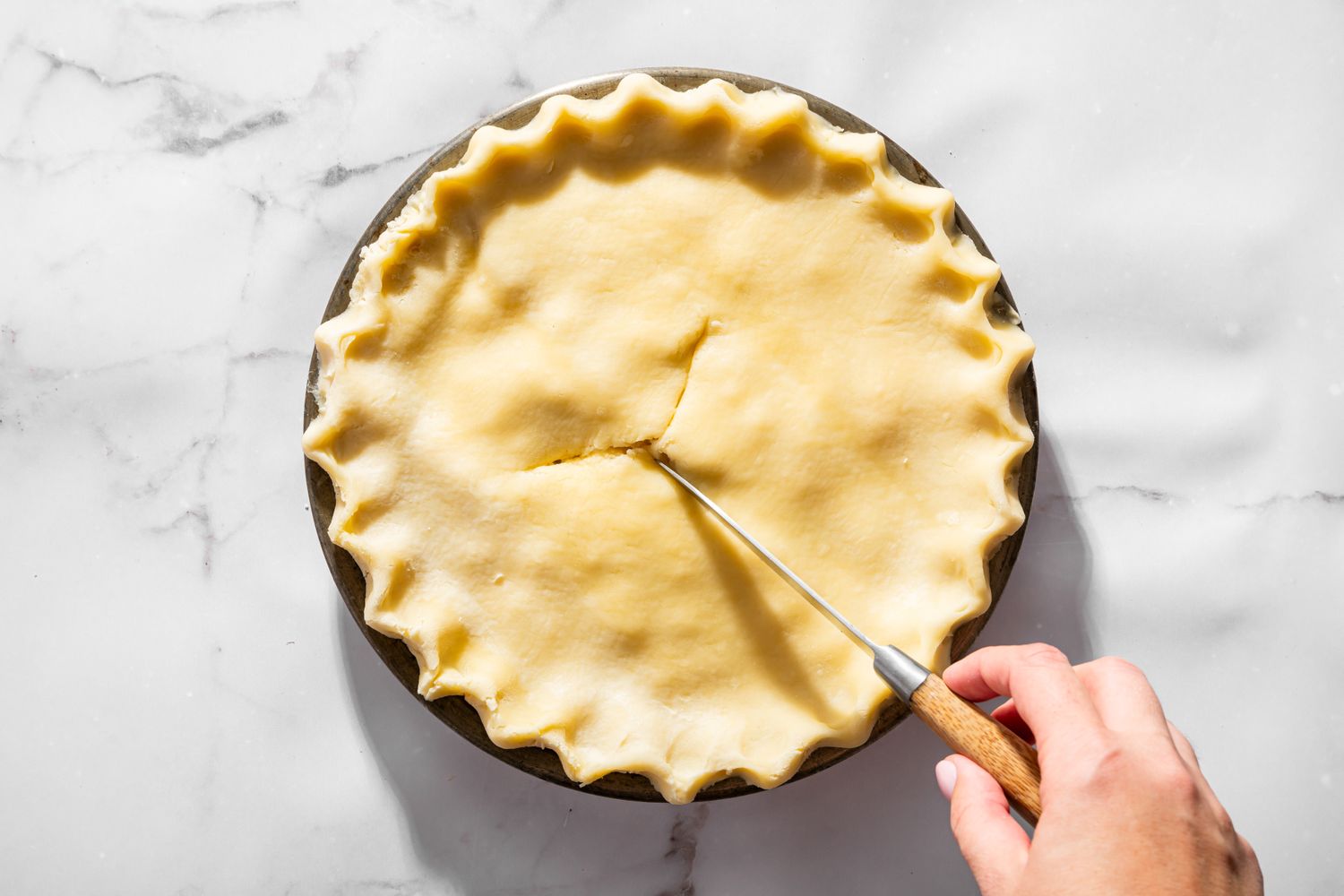 Overhead view of cutting slots in the top of the pie crust for Moravian Chicken Pie recipe