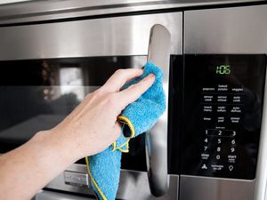 Hand Wiping the Exterior of a Mounted Microwave 